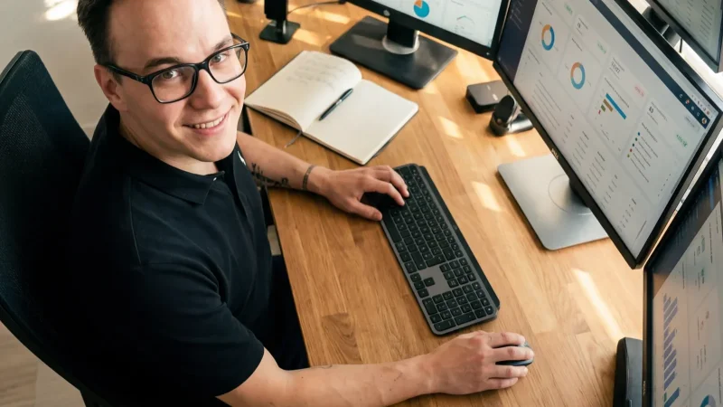 Aufgeräumter Schreibtisch mit mehreren Bildschirmen und Business-Apps von oben